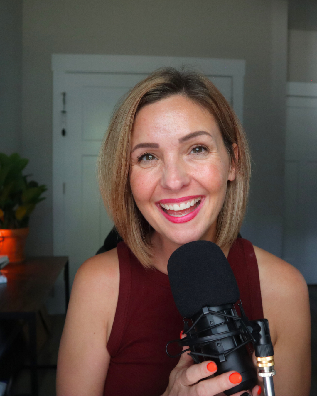 April Poynter laughing at her podcast microphone